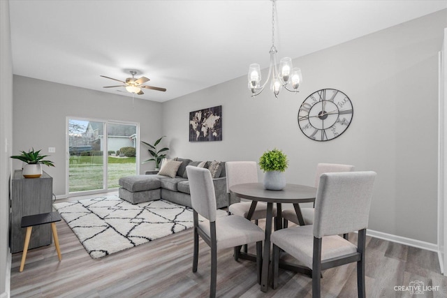 dining room with ceiling fan with notable chandelier and wood-type flooring