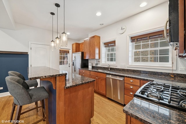 kitchen featuring appliances with stainless steel finishes, a center island, brown cabinets, and light wood finished floors