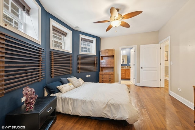 bedroom with a ceiling fan, ensuite bathroom, baseboards, and wood finished floors