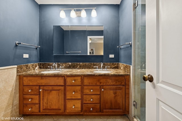 bathroom with tile walls, a sink, a shower stall, and double vanity