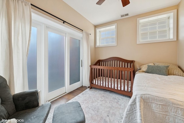 bedroom with access to exterior, wood finished floors, visible vents, and a ceiling fan