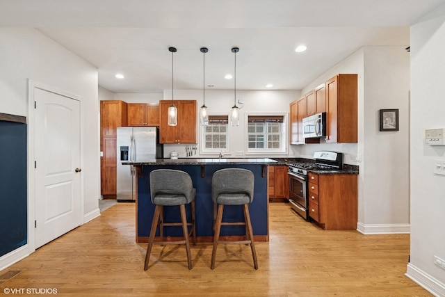 kitchen featuring stainless steel appliances, light wood-style flooring, a breakfast bar area, and brown cabinetry