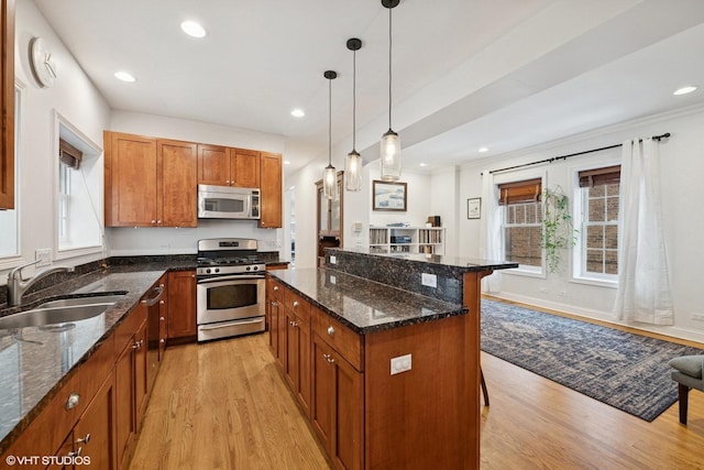 kitchen featuring a sink, a kitchen breakfast bar, appliances with stainless steel finishes, a center island, and brown cabinetry