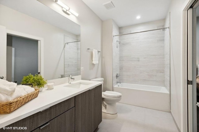 full bathroom with tile patterned flooring, vanity, tiled shower / bath combo, and toilet