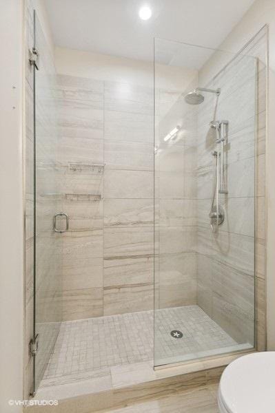 bathroom featuring toilet and a shower with door