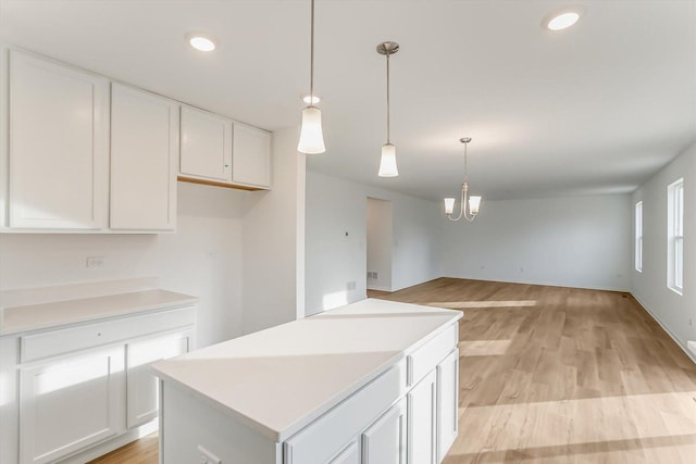 kitchen featuring decorative light fixtures, light hardwood / wood-style flooring, white cabinets, a chandelier, and a kitchen island