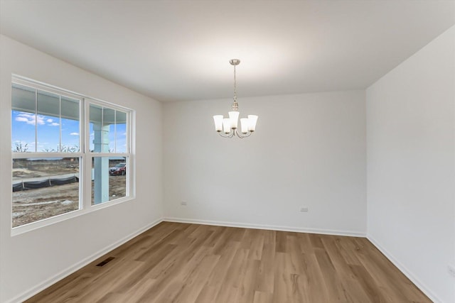 empty room featuring hardwood / wood-style flooring and a notable chandelier