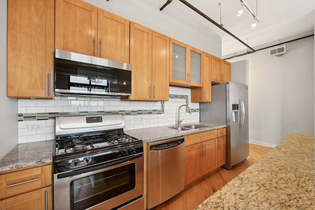 kitchen with light stone counters, light hardwood / wood-style floors, sink, and stainless steel appliances