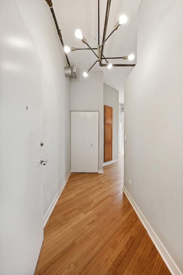 corridor with light hardwood / wood-style flooring and a notable chandelier