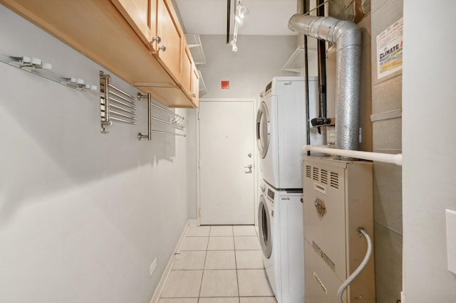 washroom featuring cabinets, light tile patterned floors, and stacked washer / dryer