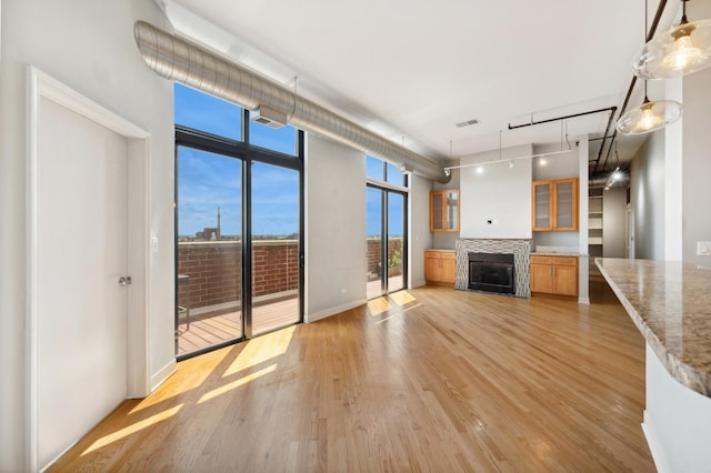 unfurnished living room with floor to ceiling windows, a fireplace, and light hardwood / wood-style flooring