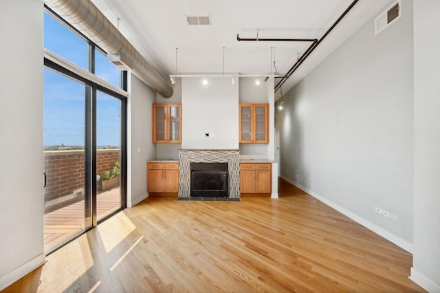 kitchen with a tile fireplace, light hardwood / wood-style floors, a wall of windows, and a healthy amount of sunlight