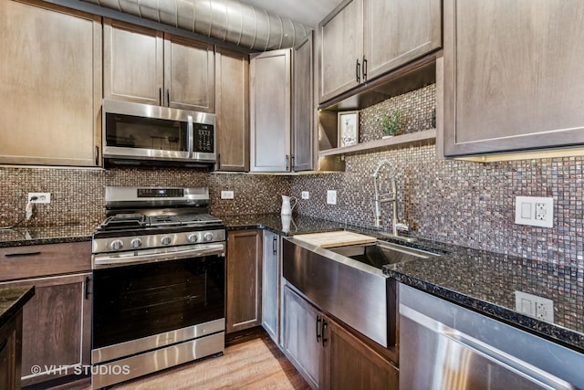 kitchen with decorative backsplash, sink, light wood-type flooring, appliances with stainless steel finishes, and dark stone counters