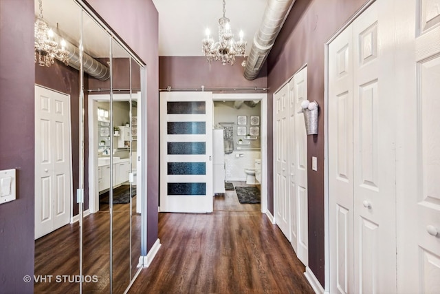 hallway with dark hardwood / wood-style floors and a notable chandelier