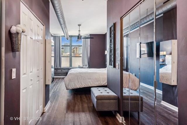 bedroom featuring a wall of windows and dark wood-type flooring