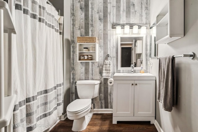 bathroom with toilet, vanity, wood walls, and hardwood / wood-style floors