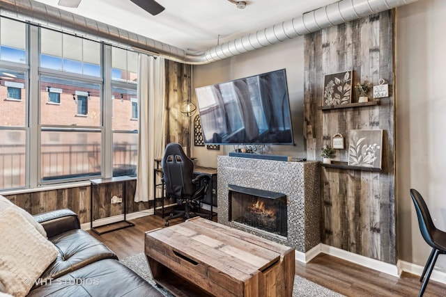 living room featuring ceiling fan, wood-type flooring, and a tiled fireplace