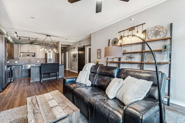 living room featuring ceiling fan, a barn door, dark hardwood / wood-style floors, and sink