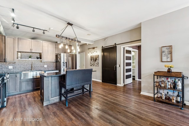 kitchen featuring a barn door, a breakfast bar area, appliances with stainless steel finishes, a kitchen island, and sink