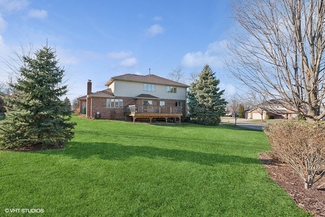 back of house featuring brick siding, a chimney, a lawn, and a wooden deck