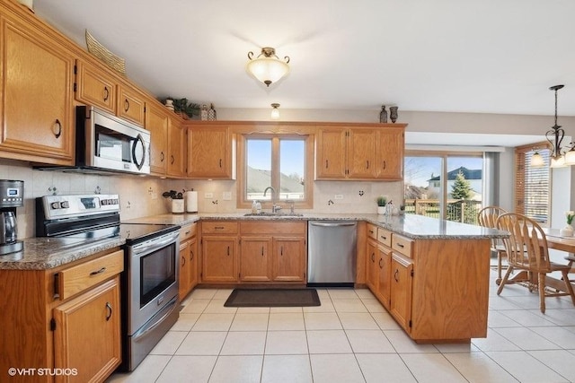 kitchen featuring light tile patterned floors, appliances with stainless steel finishes, backsplash, a peninsula, and a sink