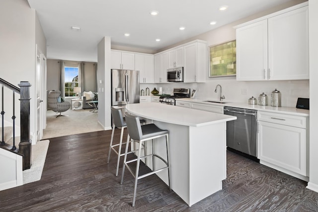 kitchen with a kitchen island, white cabinetry, stainless steel appliances, and a breakfast bar area