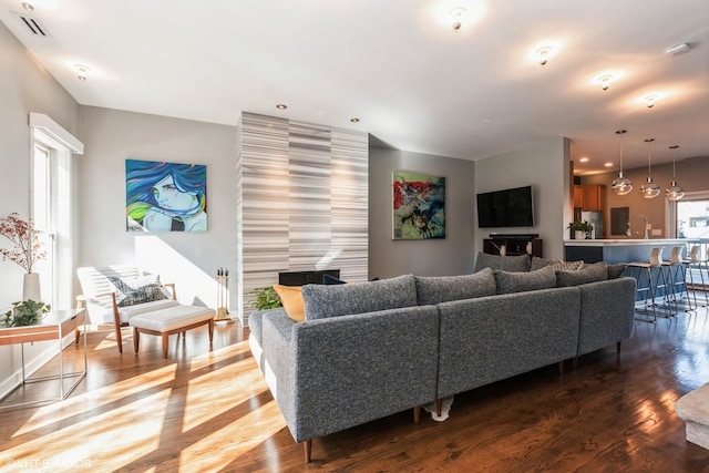 living room with dark wood-style floors, recessed lighting, visible vents, and plenty of natural light