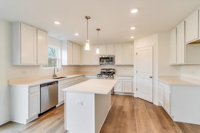 kitchen with stainless steel appliances, a kitchen island, sink, and white cabinets