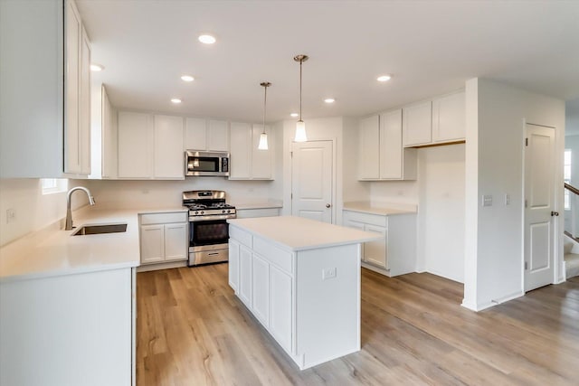 kitchen featuring a kitchen island, decorative light fixtures, white cabinetry, sink, and stainless steel appliances