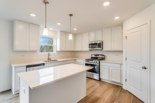 kitchen with appliances with stainless steel finishes, sink, hanging light fixtures, and white cabinets