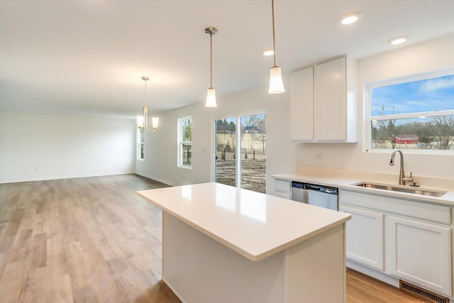 kitchen featuring decorative light fixtures, dishwasher, sink, white cabinets, and a center island