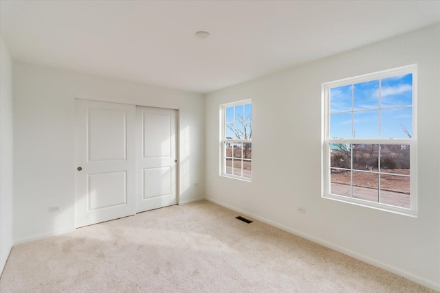 unfurnished bedroom featuring a closet and light carpet