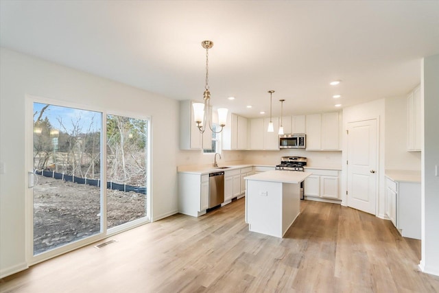 kitchen with pendant lighting, sink, appliances with stainless steel finishes, a center island, and white cabinets