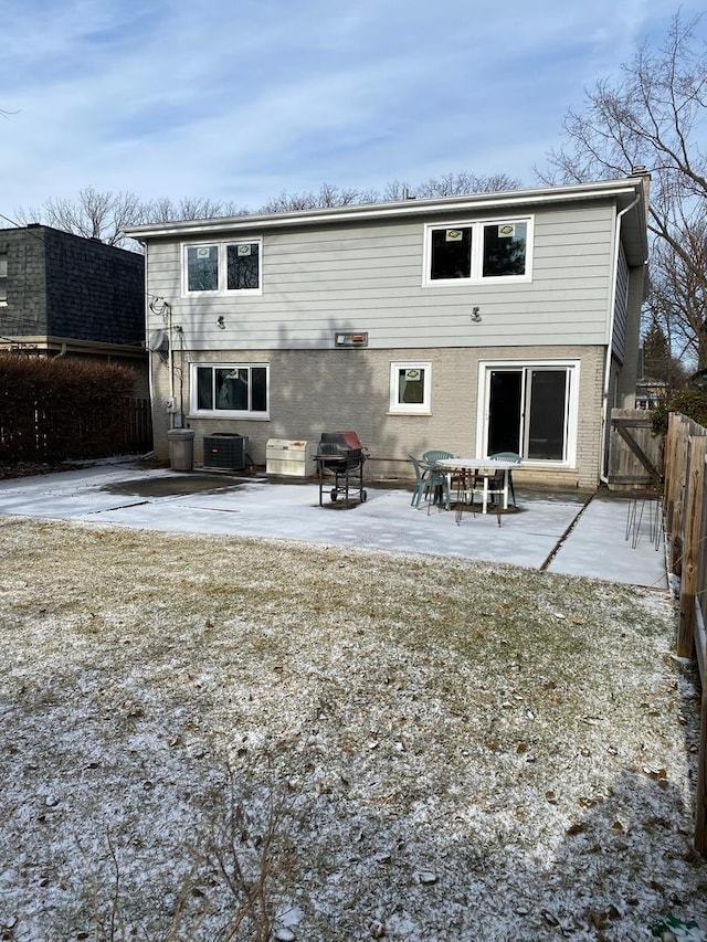 snow covered rear of property with central AC unit and a patio area