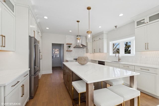 kitchen with white cabinetry, high quality fridge, wall chimney exhaust hood, and a kitchen island