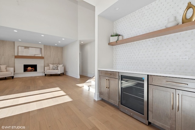 bar featuring a high ceiling, beverage cooler, and light wood-type flooring