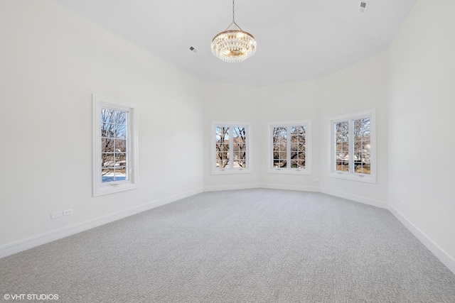 carpeted spare room featuring a notable chandelier