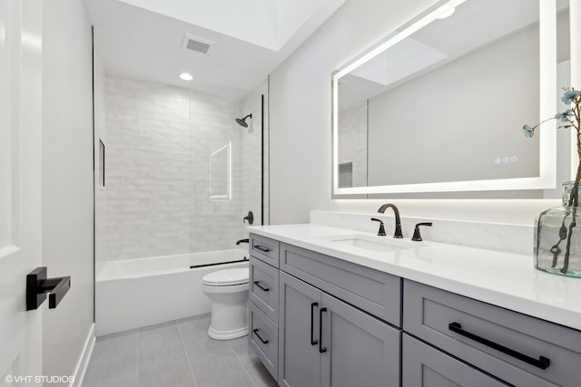 full bathroom with toilet, a skylight, vanity, tiled shower / bath combo, and tile patterned flooring