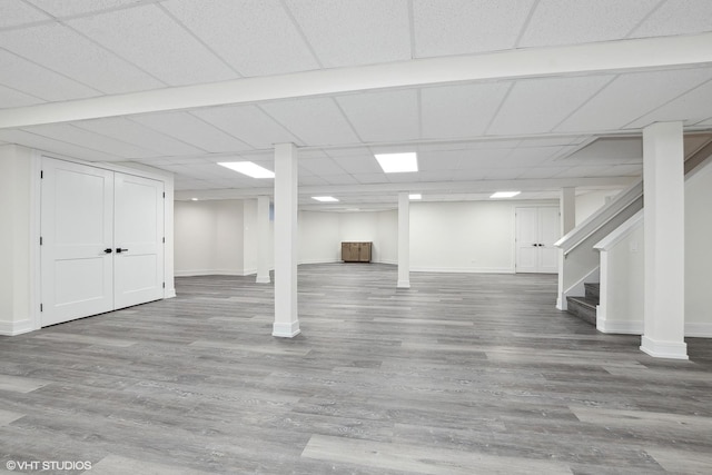 basement featuring a paneled ceiling and wood-type flooring