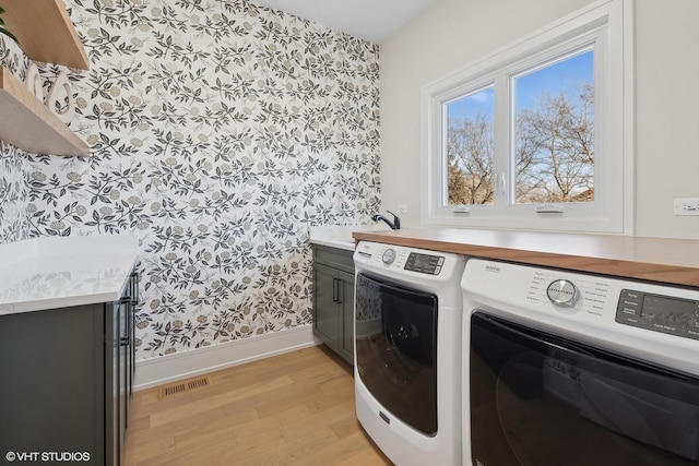 laundry room featuring cabinets, separate washer and dryer, sink, and light hardwood / wood-style floors