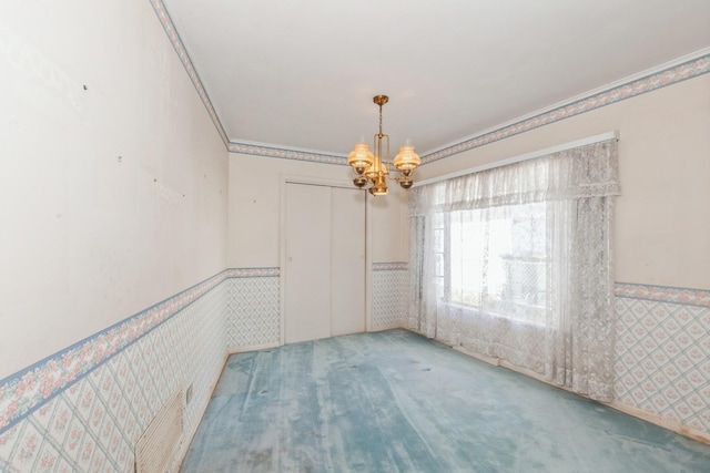 carpeted empty room with a notable chandelier