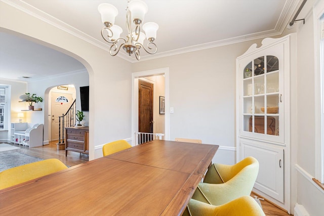 dining area with an inviting chandelier, a baseboard heating unit, crown molding, and light wood-type flooring