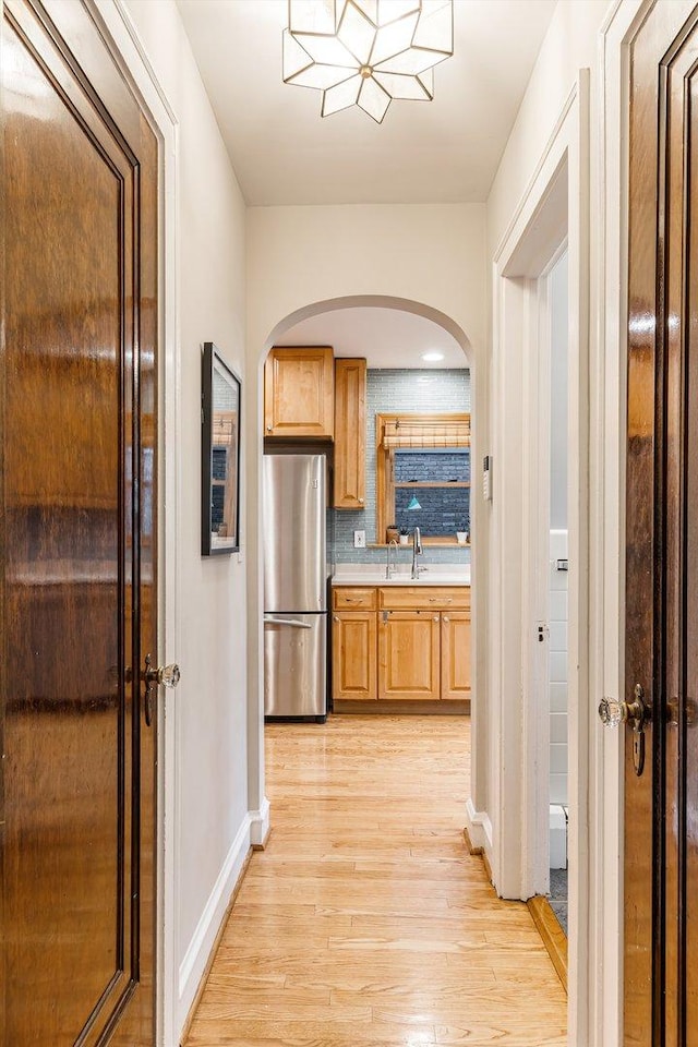 kitchen with sink, stainless steel fridge, backsplash, and light hardwood / wood-style flooring