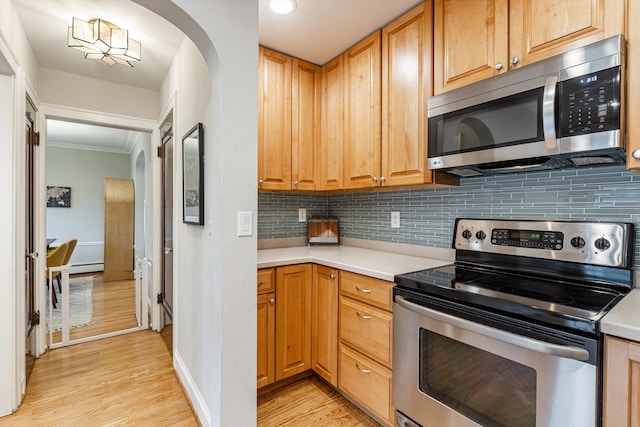 kitchen featuring ornamental molding, decorative backsplash, light hardwood / wood-style flooring, and stainless steel appliances