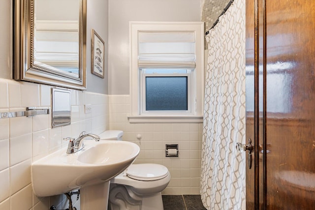 bathroom with tile patterned flooring, tile walls, and toilet