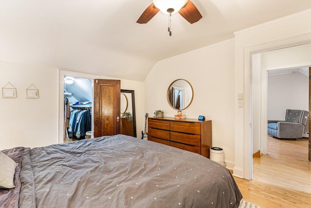 bedroom with lofted ceiling, ceiling fan, ornamental molding, a spacious closet, and light wood-type flooring