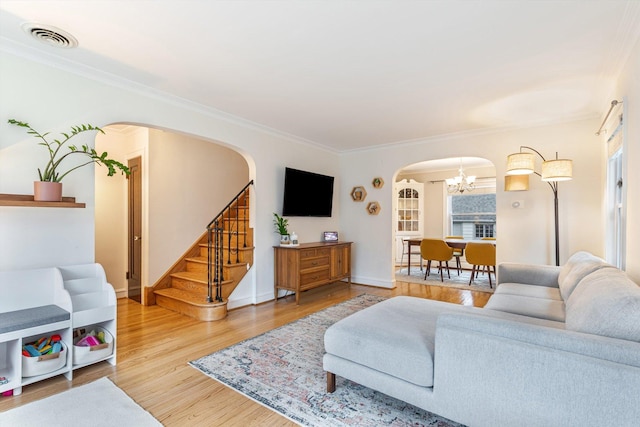 living room with hardwood / wood-style flooring, crown molding, and a notable chandelier