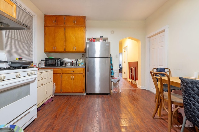 kitchen featuring stainless steel fridge, dark hardwood / wood-style floors, extractor fan, and white gas stove