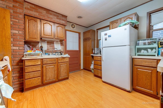 kitchen featuring sink, tasteful backsplash, white refrigerator, light wood-type flooring, and ornamental molding