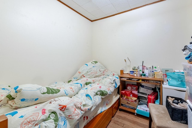 bedroom featuring ornamental molding and light hardwood / wood-style flooring